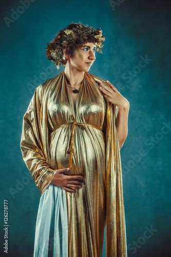 Pregnant Woman In Golden Toga And Wreath Posing Like A Greece Fertility