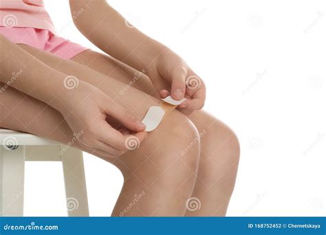 girl putting sticking plaster  leg  white background stock photo