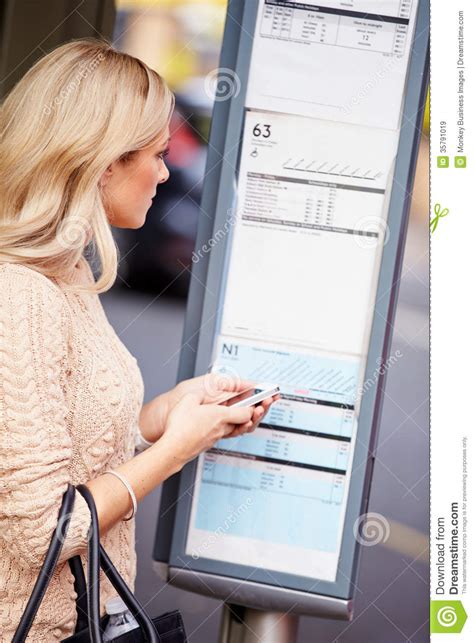 woman at bus stop with mobile phone reading timetable royalty free stock images image 35791019