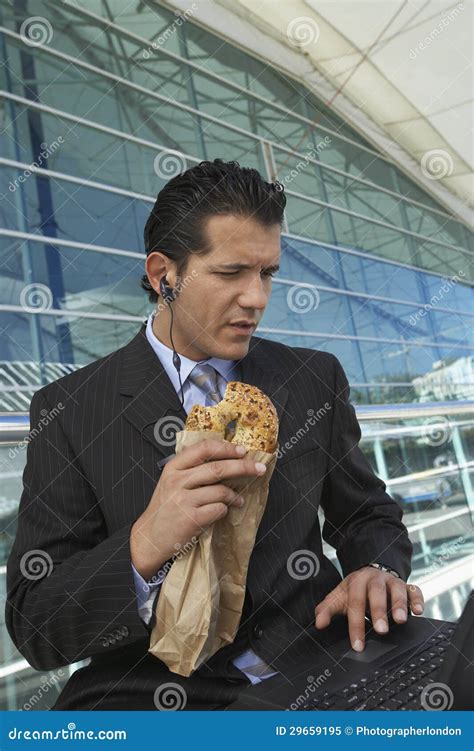 businessman  laptop eating bagel stock image image  person