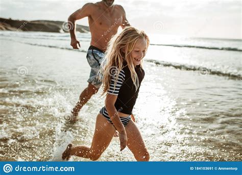 Girl Running In Water With Her Father At The Beach Stock