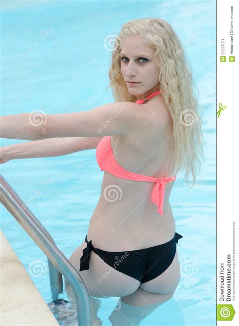 woman in bikini holding the pool steps and looking back