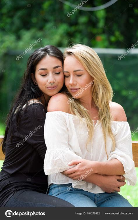 a pair of proud lesbian in outdoors brunette woman is hugging a blonde