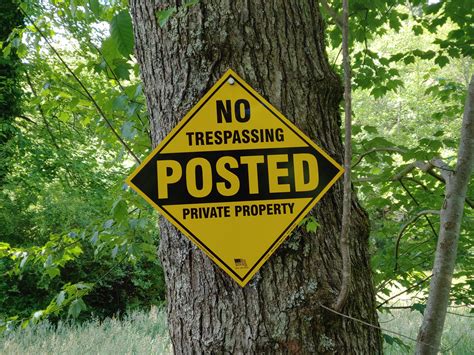 trespassing posted private property yellow  orange aluminum  supporting sign