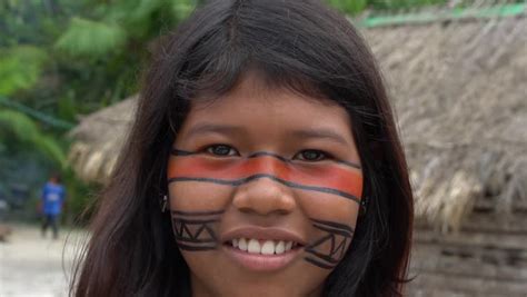 cute native brazilian girl looking to the camera at an indigenous tribe in the amazon stock