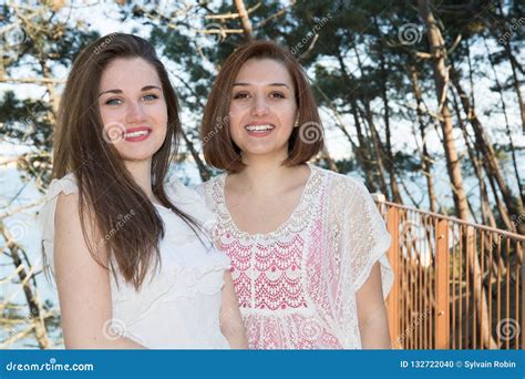 Lesbian Couple Standing At The Beach In Love Looking Into Camera Stock