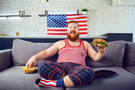 overweight funny man eating a burger snacking while sitting on the