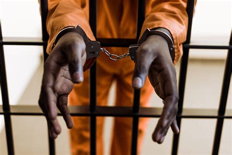cropped image  african american prisoner  handcuffs  prison bars