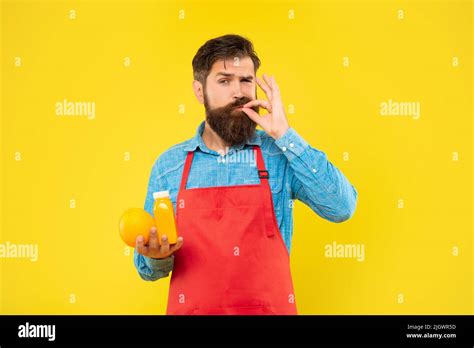 Man In Apron Licking Finger Holding Orange And Juice Bottle Yellow