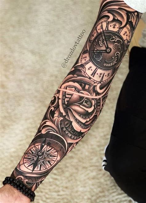 A Person With A Tattoo On Their Arm Holding A Clock And Compass In His Hand
