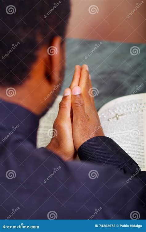 man folding hands praying  open bible lying  front