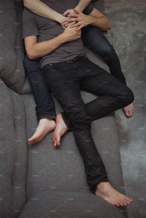 romantic gay couple embracing on sofa at home high quality stock