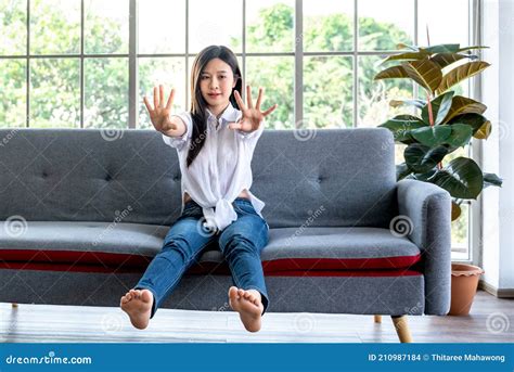 Woman Sitting On A Sofa Stretching Her Arms And Legs To Relax The