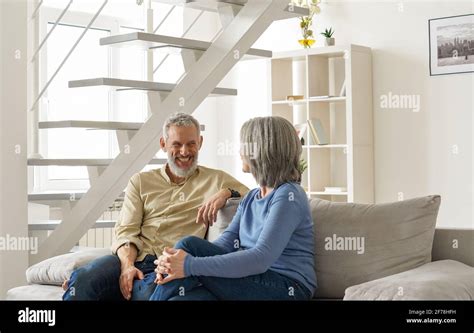 Happy Mature Older Couple Laughing And Talking Sitting At Home On Couch