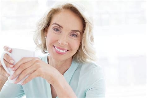 mature woman smiling with cup of tea photograph by science photo