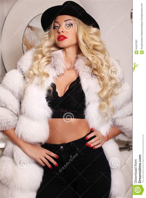 woman with long blond hair wears luxurious white fur coat stock image