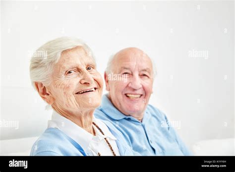 Happy Retired Couple Sitting On The Sofa At Home Or In Retirement Home