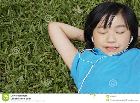 girl wearing earphones while lying on grass stock