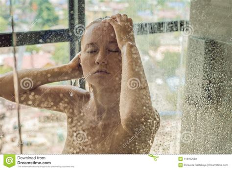 beautiful woman in the shower behind glass with drops on the background