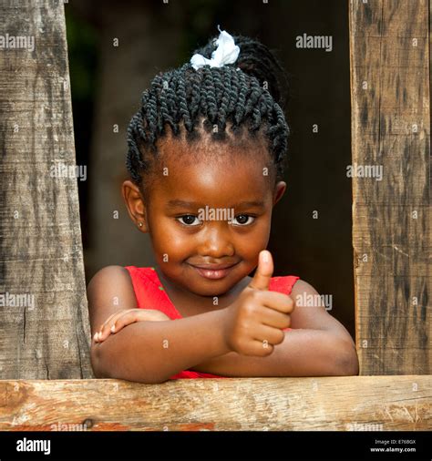 Portrait Of Small African Girl Doing Thumbs Up At Wooden Fence Stock