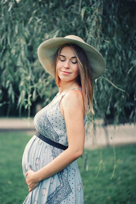 Pregnant Young Caucasian Woman Wearing Long Blue Dress And Rustic