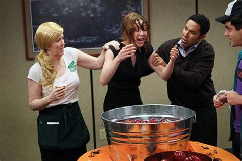 four people standing around an orange table with a metal bucket on it
