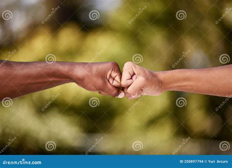 Fist Bump Of Two Interracial Men Outdoor Against A Blur Background