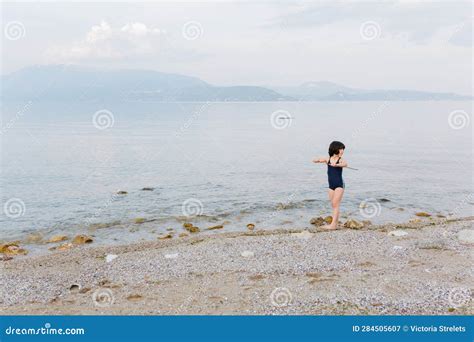 girl in blue swimsuit standing on the beach of the lake stock image