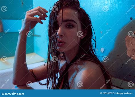 playful brunette posing in a bathtub wearing underwear in the neon