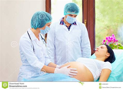 o doutor apalpa o abdômen da mulher gravida durante o parto imagem de stock imagem de entrega