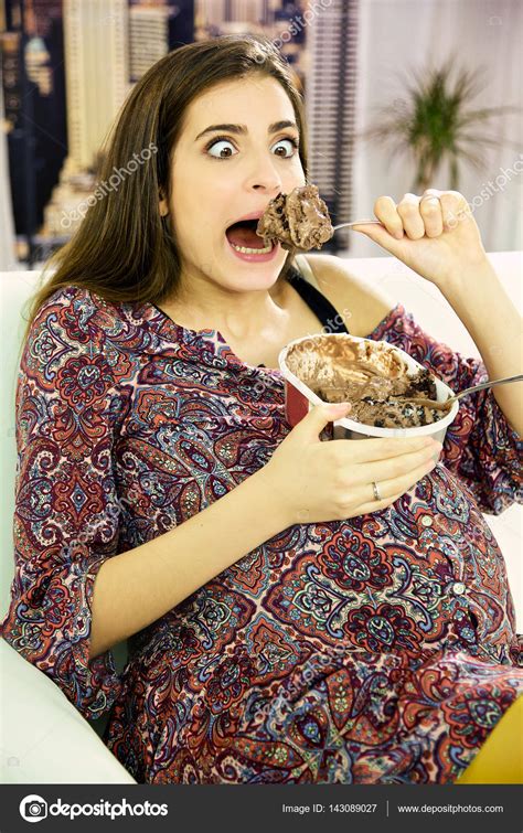 Смешная красивая беременная женщина ест большую ложку шоколадного