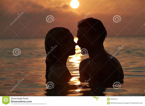 Silhouette Of Romantic Couple Standing In Sea Stock Image