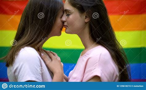 cute lesbians hugging lovingly rainbow flag on background