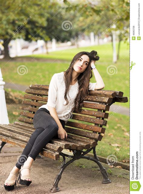Pensive And Elegant Beautiful Woman Sitting On Old Bench