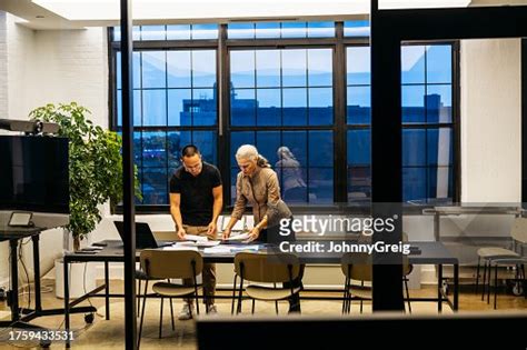 Mature Art Director And Male Assistant Organizing Documents High Res