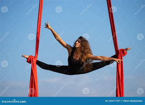 beautiful and flexible female circus artist dancing with aerial silk on