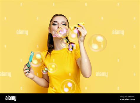 Happy Beautiful Woman Blowing Soap Bubbles Isolated Over Yellow
