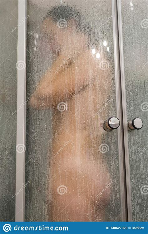 beautiful woman in the shower behind glass with drops woman in the