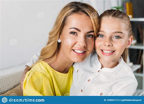 Smiling Mother And Daughter Sitting On Couch And Looking Stock Image