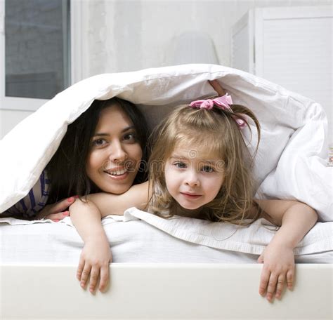 Portrait Of Mother And Daughter Laying In Bed And Smiling