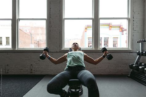 strong healthy woman working out in gym free weights by stocksy