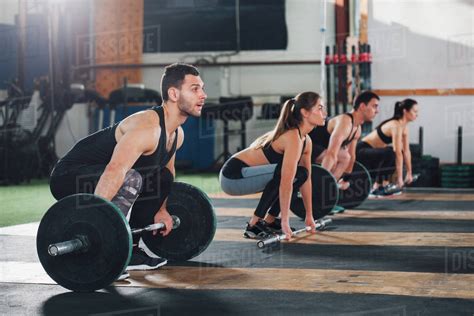 Dedicated Male And Female Athletes Lifting Barbells At Gym Stock