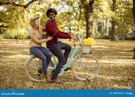 Multiracial Couple Riding On A Bicycle At The Autumn Park Stock Image