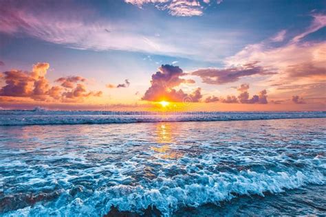 Sunset Over Ocean Splashing Ocean Wave In Front Of