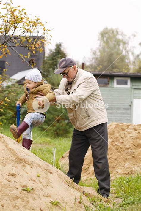 Grandpa Helps Grandson To Get On A Sand Hill Royalty Free Stock Image