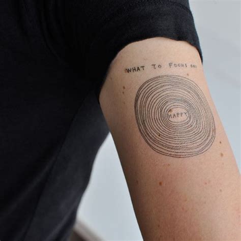 Simple Homemade Black Ink Circles With Lettering Tattoo On Arm