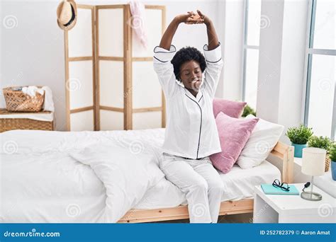 Young African American Woman Waking Up Sitting On Bed At Bedroom Stock