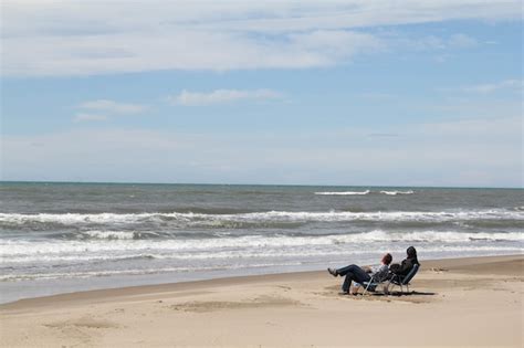 shot van twee mensen die op de stoelen op het strand zitten en naar de golven van de oceaan