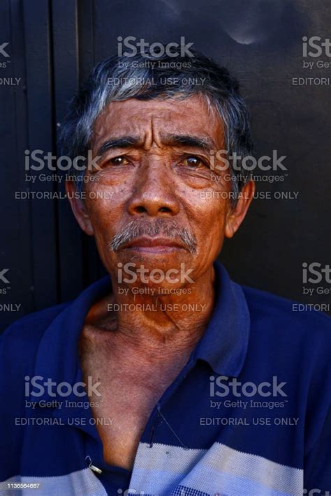 A Mature Filipino Man Rests On A Sidewalk And Poses For The Camera