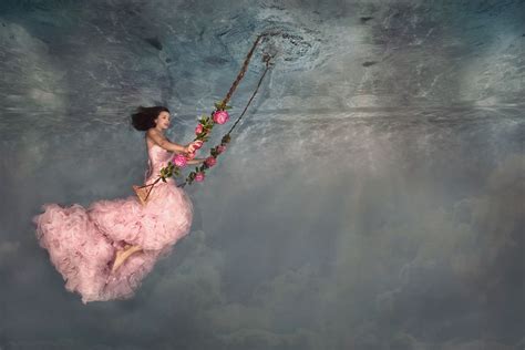 A Woman In A Pink Dress Floating On A Swing With Flowers Hanging From